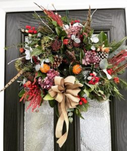 A large luxury Christmas door wreath made from fresh botanical spruces, dried herbs, beuatufl luxury embellishments, a huge natural hessian bow. It's elegant posh and high end very classy, designed and handmade by Green Onion Landscaping in Hartburn Stockton on Tees