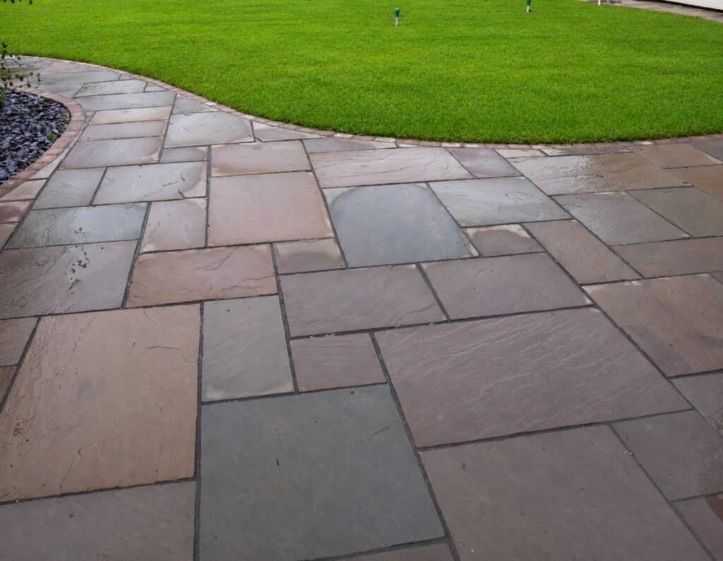 Curved sandstone patio with brick edging and lawn installed by Green Onion Landscaping in Stockton-on-Tees